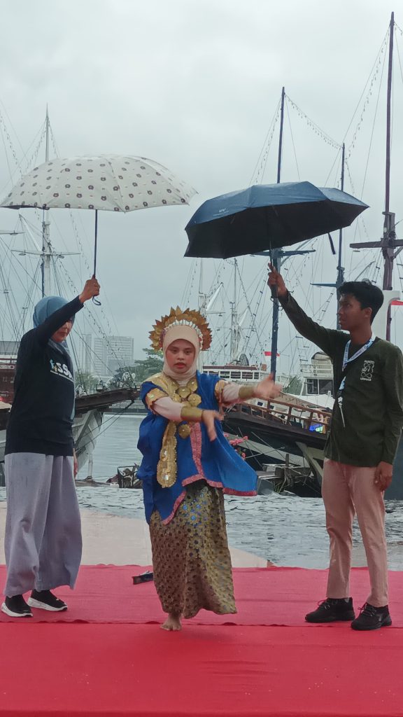 Nayla sedang menari dipayungi ibunya dan Reski, relawan Pusdis